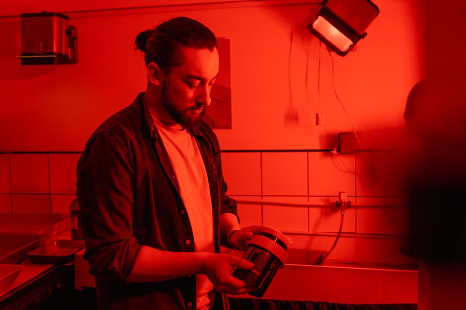 Evde karanlık odada film yıkama işlemini gösteren bir kişi yakın çekim